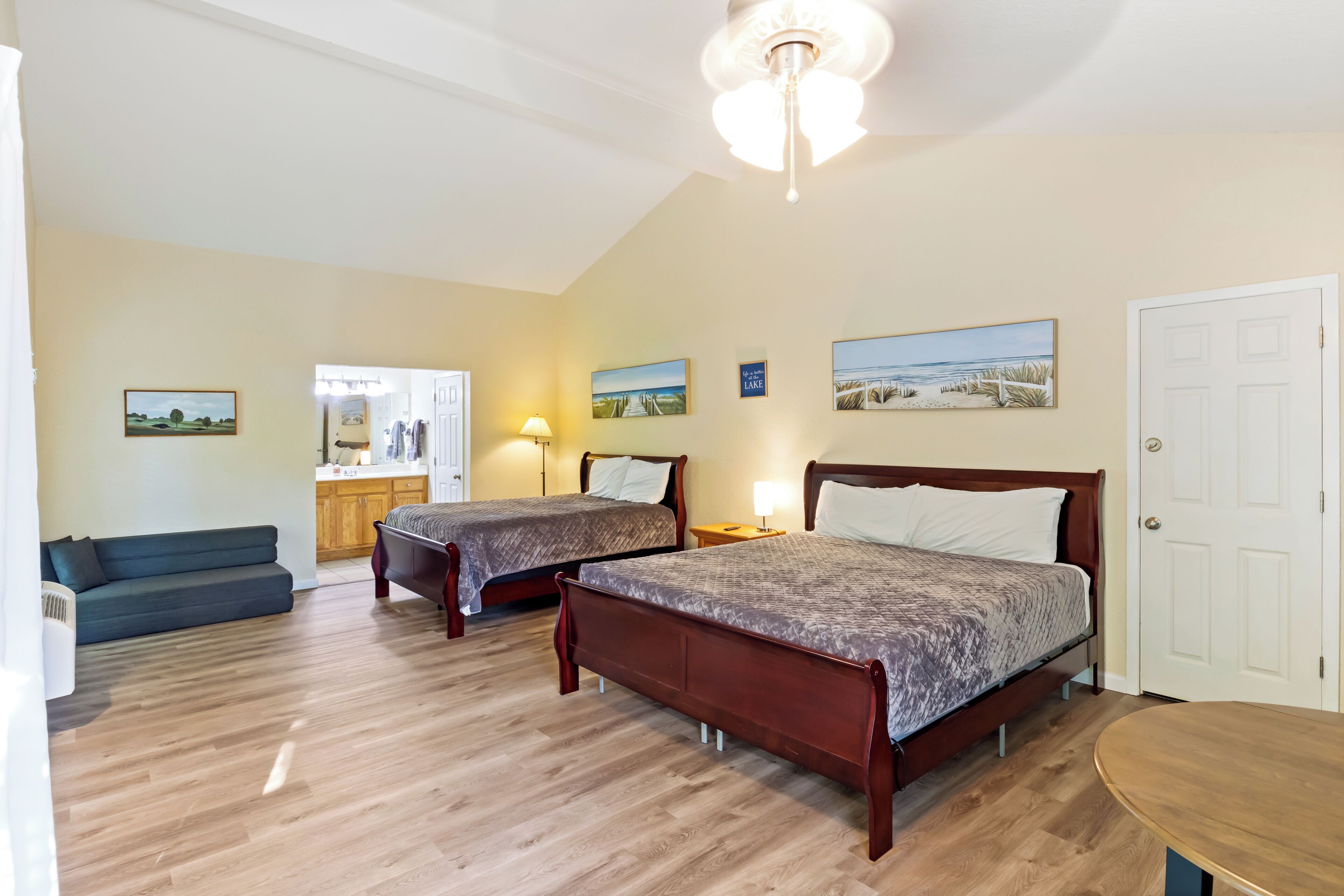 A bedroom with two beds, a sofa, a desk, and a door.