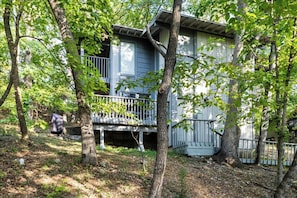 A two-story house with a balcony, surrounded by trees. - Private Pool, Patio: Dog-friendly Ozarks Retreat (Osage Beach)