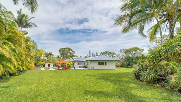 Uma casa com gramado bem cuidado, um pequeno espaço de pátio e um guarda-sol vermelho.