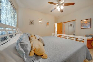 A bedroom with a bed, a ceiling fan, a window with curtains, and a door. - Lush Puna Coast Escape! Spacious Home w/ Pool (Keaau)