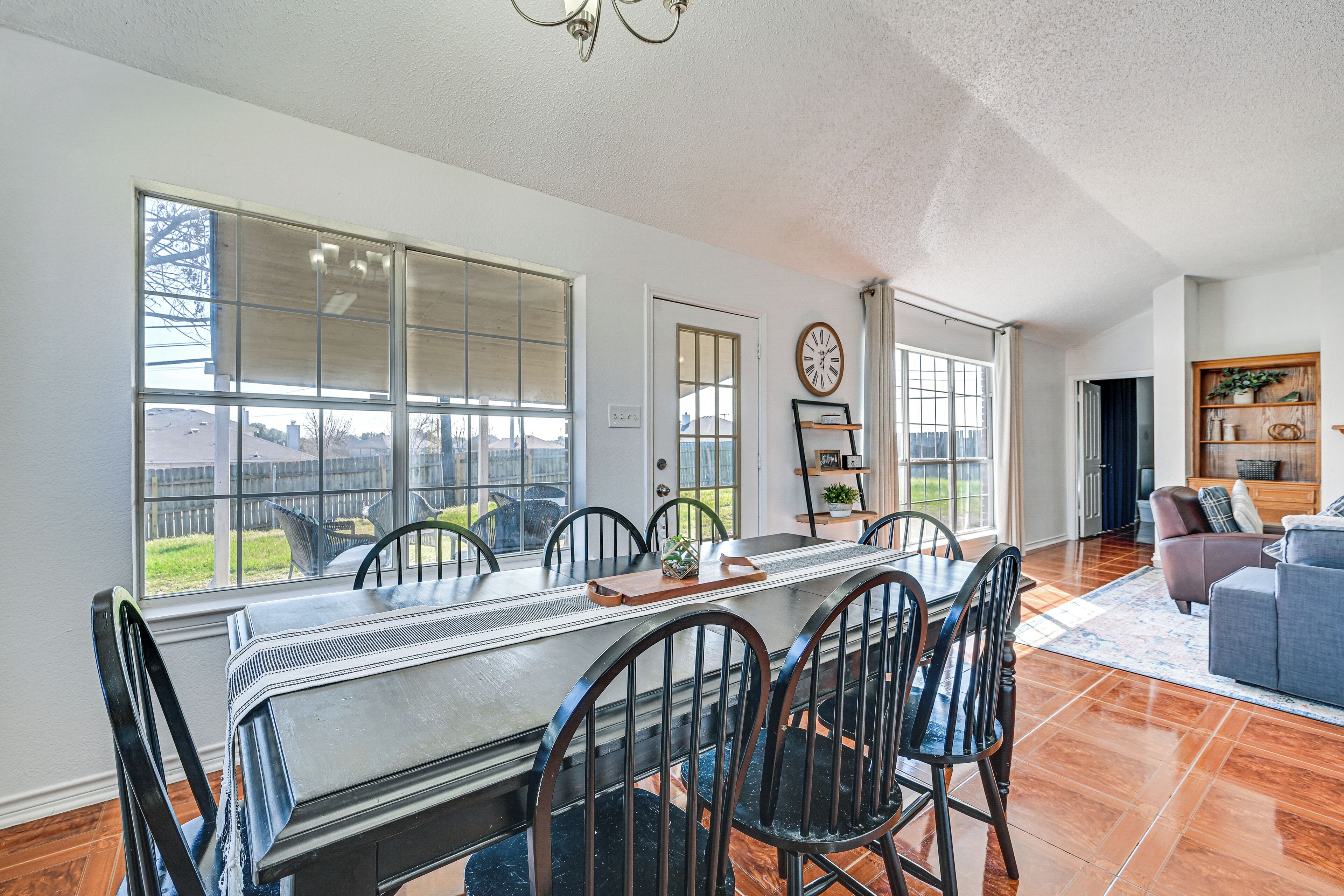 A spacious dining area with a long table, chairs, and a view of the outdoors.