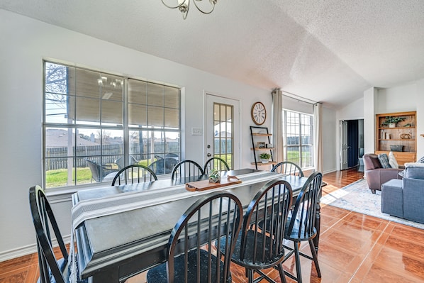 A spacious dining area with a long table, chairs, and a view of the outdoors.