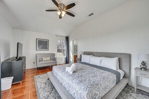 A bedroom with a bed, a ceiling fan, a dresser, a chair, and a window.