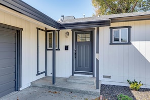 A residential building with a grey door, a small window, and a mailbox.