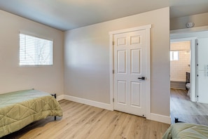 A bedroom with a bed, a door, and a window.