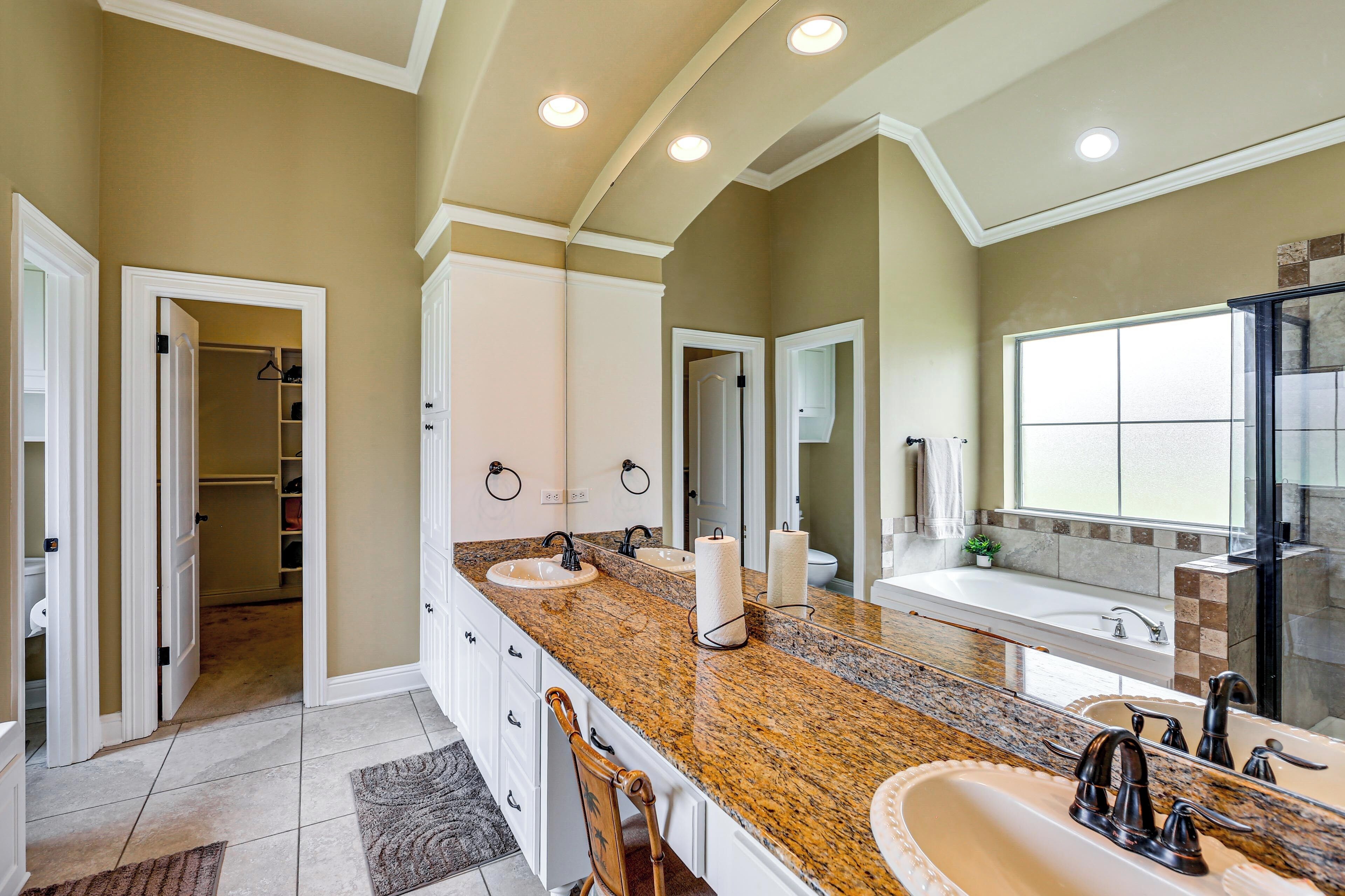 A bathroom with two sinks, a large mirror, and a walk-in closet.