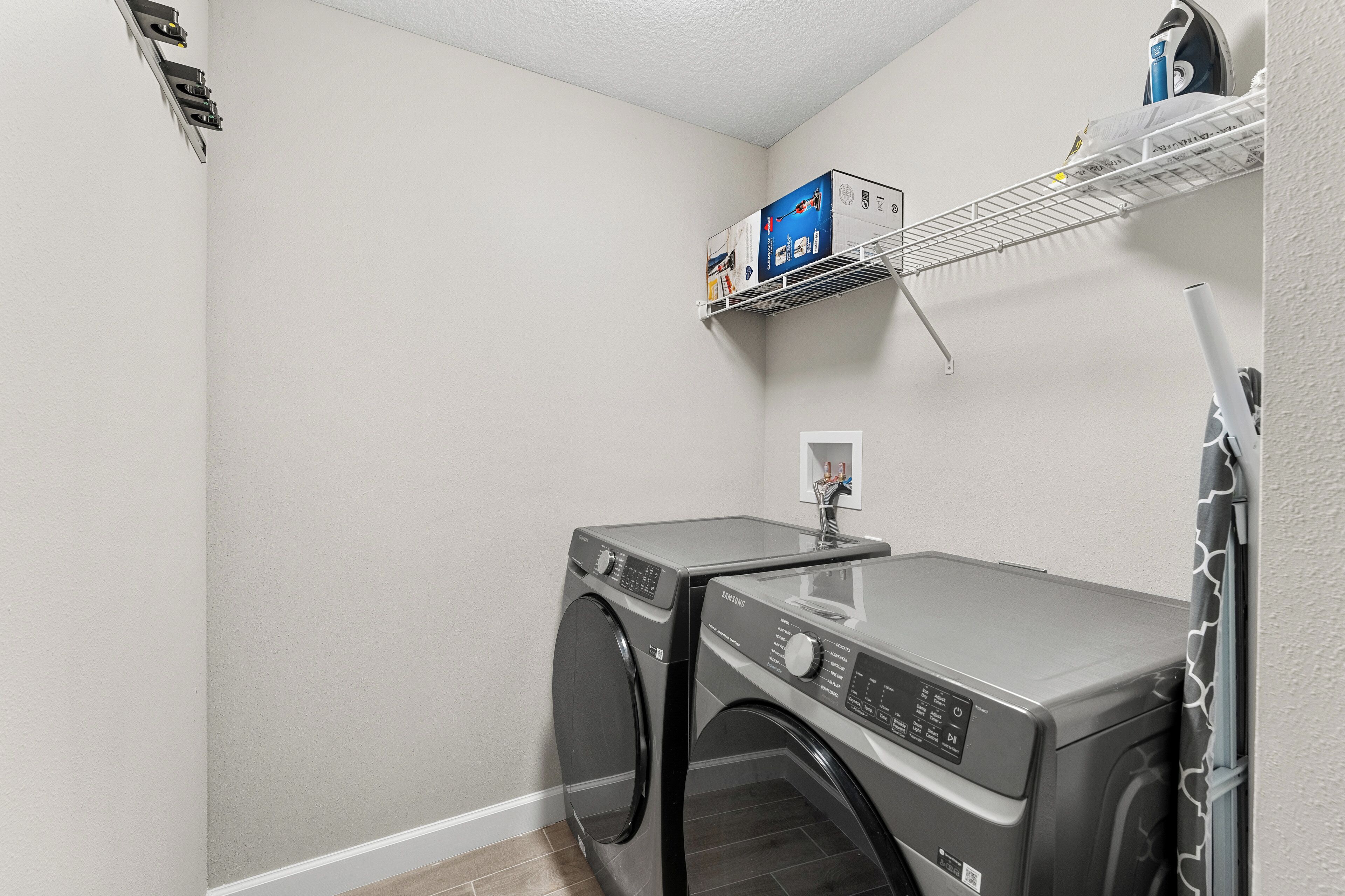 A laundry room with a washing machine, a dryer, and a shelf with boxes.