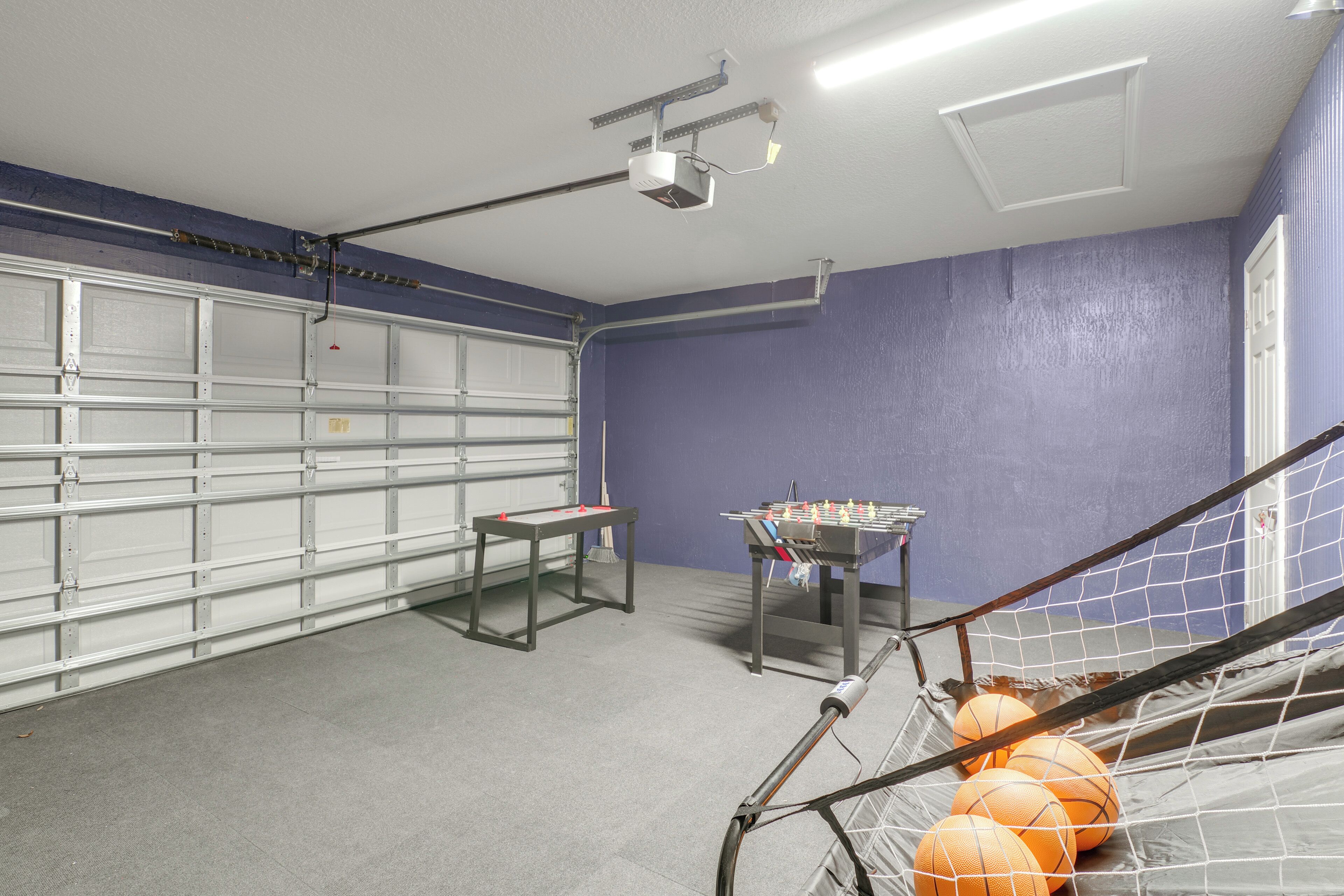Un garaje con una mesa, una mesa de futbolín y balones de baloncesto.