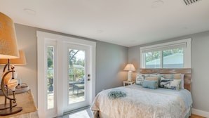 A bedroom with a bed, two bedside lamps, a window, and a door leading to an outdoor area. - 7 Mi to Indian Rocks Beach: Breezy Family Retreat! (Largo)