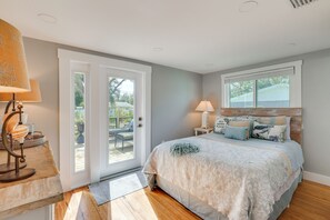 A bedroom with a bed, two bedside lamps, a window, and a door leading to an outdoor area. - 7 Mi to Indian Rocks Beach: Breezy Family Retreat! (Largo)