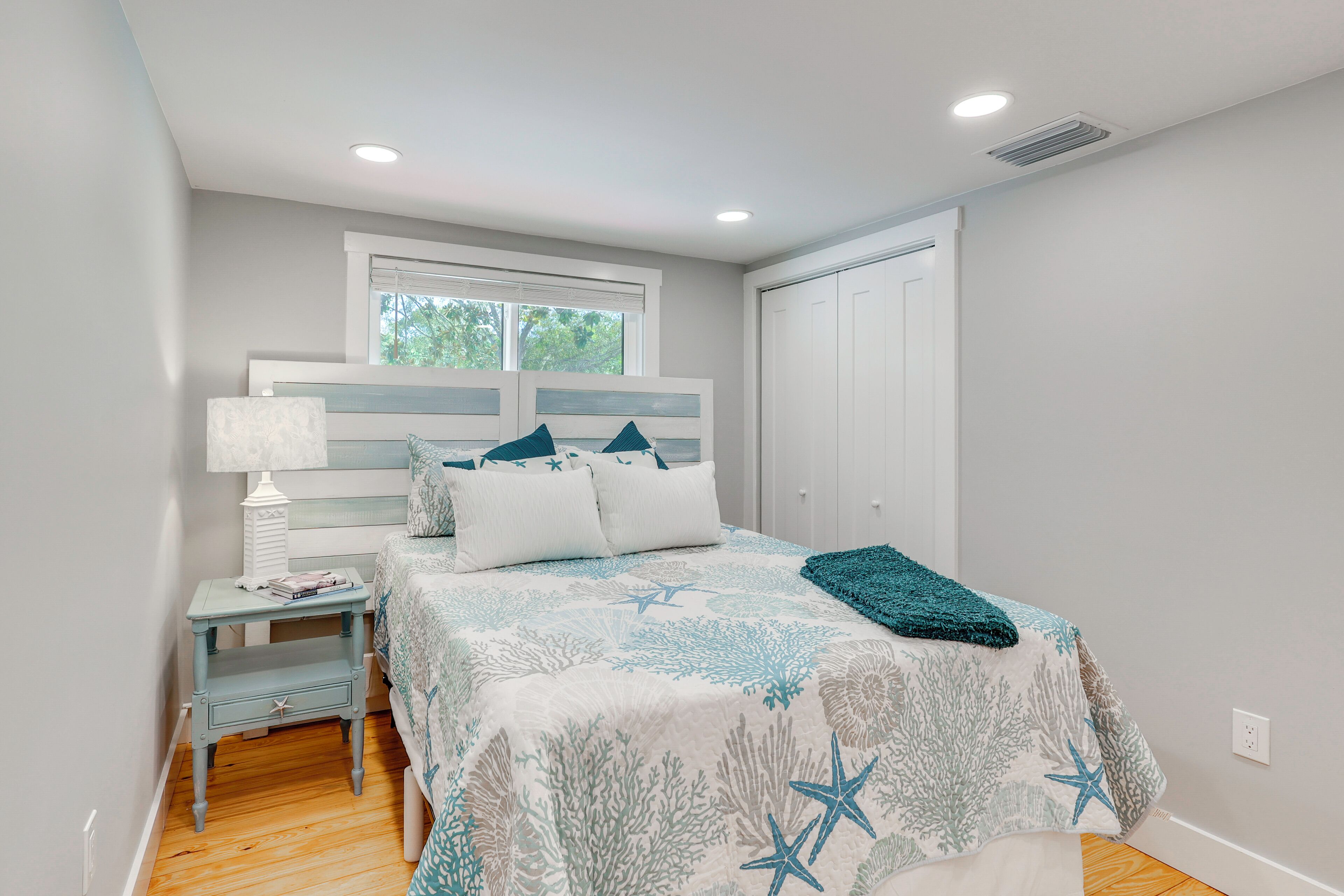 Une chambre à coucher avec un lit, une table de chevet, une lampe et une fenêtre.