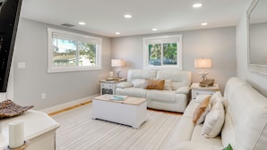 A living room with a white sofa, a coffee table, and two bedside tables with lamps. - 7 Mi to Indian Rocks Beach: Breezy Family Retreat! (Largo)