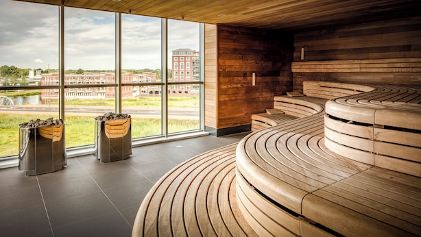 Ein modernes Interieur mit großen Fenstern, einer gebogenen Holzbank und Blick auf ein Gebäude gegenüber.