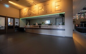 Un comptoir d’accueil avec les panneaux « RÉCEPTION » et « HÔTELS FLETCHER » bien visibles.