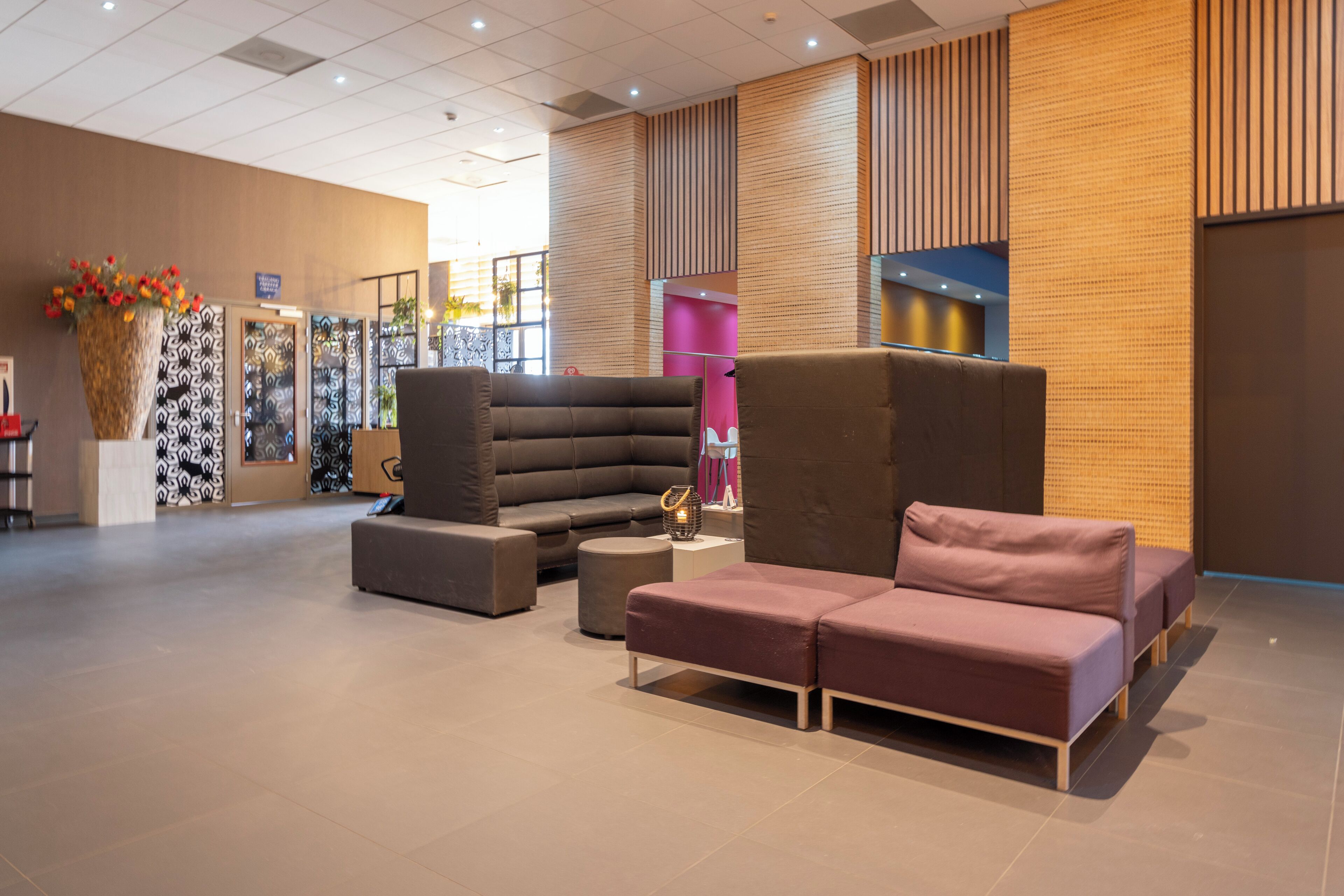 Een moderne lobby met een modulaire bank, een voetenbankje en een decoratieve vaas met bloemen.