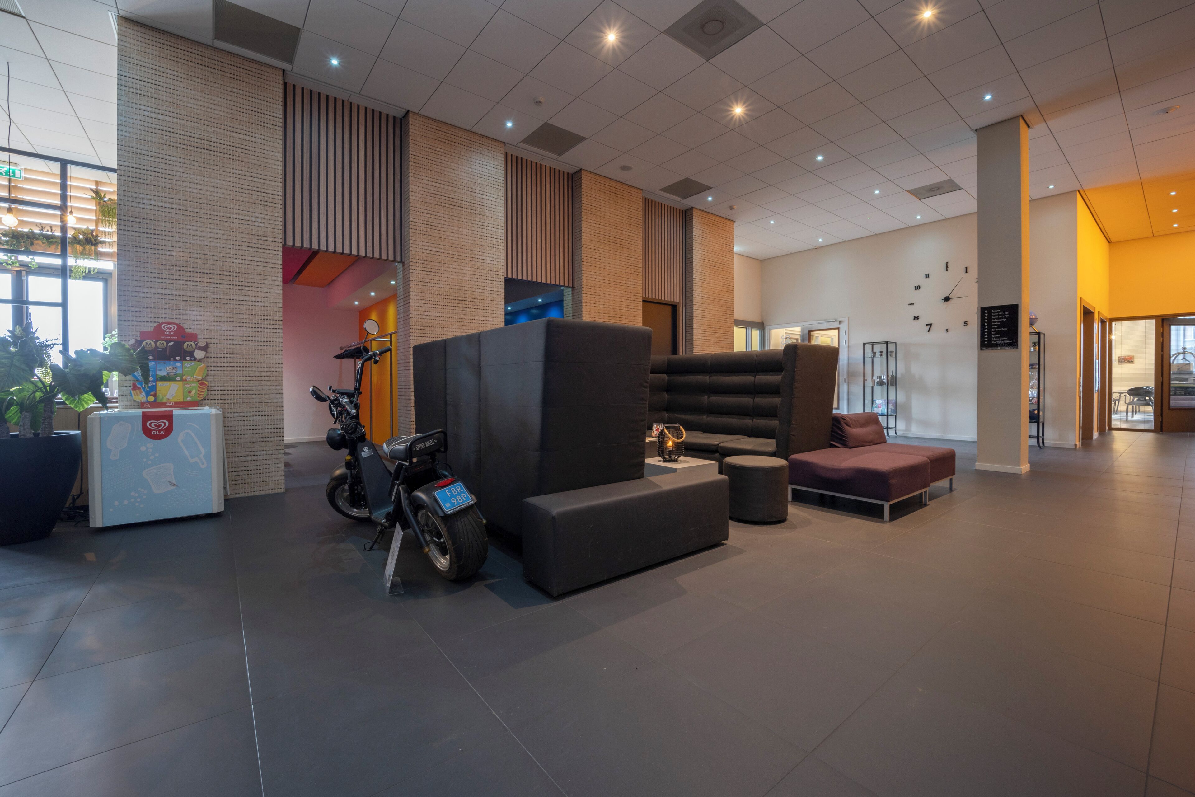 A modern lobby with a seating area, a motorcycle, and a reception desk.