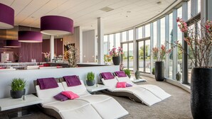 A modern lounge area with reclining chairs, a reception desk, and large windows.