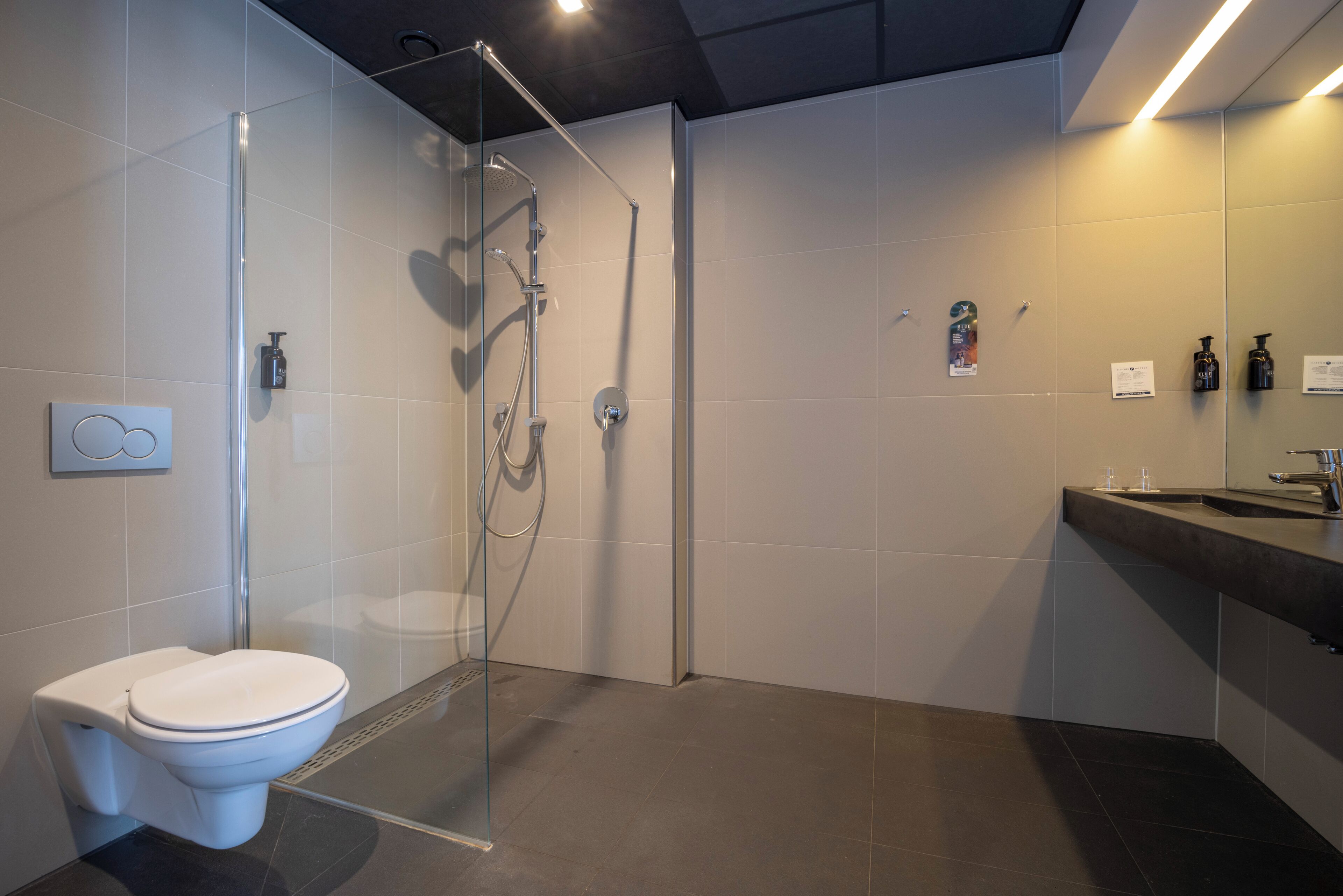 Een moderne badkamer met een douchecabine van glas, een toilet en een wastafel met spiegel.
