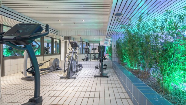 A gym with exercise equipment, a tiled floor, and a wall with green plants. - Everything You Need For The Perfect Vacation! Indoor Pool, Free Breakfast! (Nieuwegein)