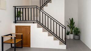 Un escalier avec des rampes noires, une porte en bois et des plantes en pot.