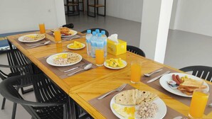 Une table dressée pour le petit-déjeuner, avec des assiettes de nourriture, des boissons et une boîte de mouchoirs.