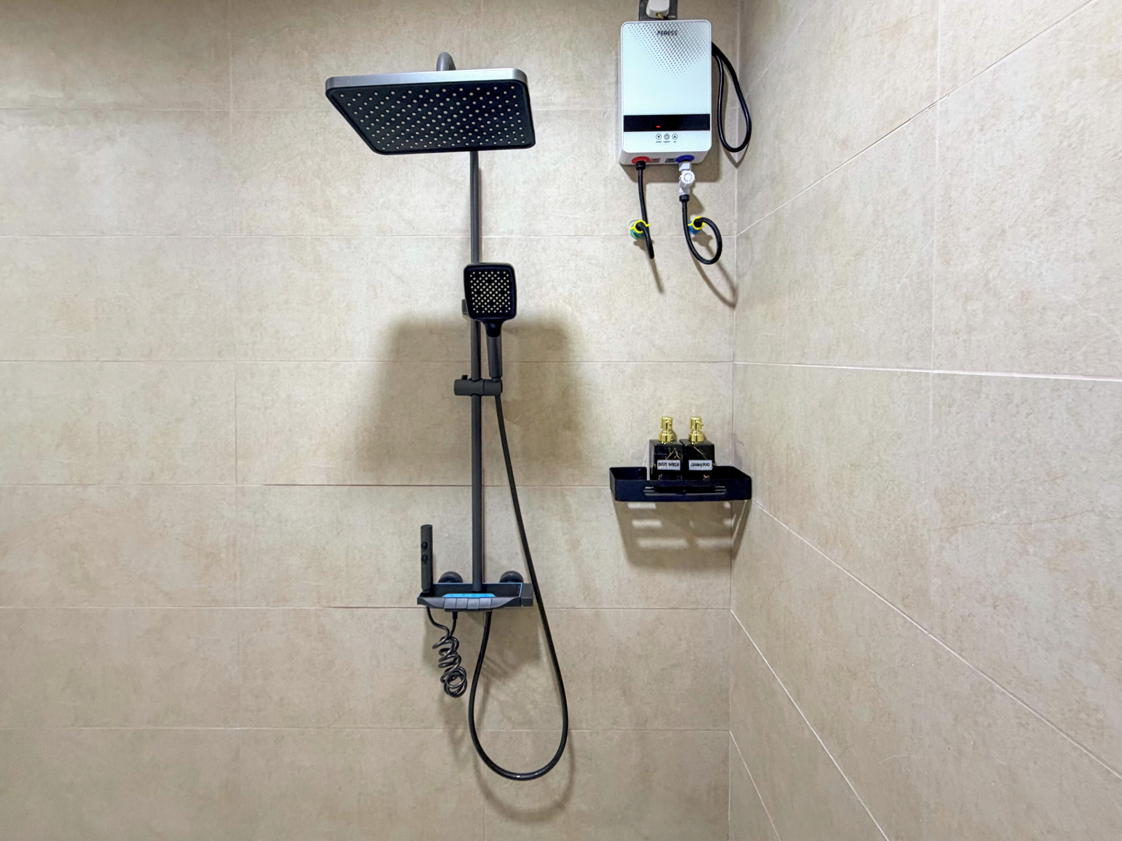 Una doccia con soffione a mano, comandi a parete e dispenser per sapone.