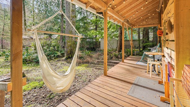 A wooden deck with a hammock, outdoor seating, and a view of a forested area. - 5 Mi to Mt Rainier Park: Unique & Rustic Getaway (Ashford)