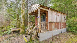 A rustic cabin labeled 'THINHOUSE' with a wooden exterior, a porch, and a staircase leading to the entrance. - 5 Mi to Mt Rainier Park: Unique & Rustic Getaway (Ashford)