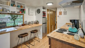 A modern kitchen with wooden countertops, a built-in stove, and bar stools. - 5 Mi to Mt Rainier Park: Unique & Rustic Getaway (Ashford)