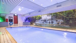A swimming pool with a waterfall mural, tiled walls, and a red door.