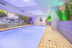Ein Innenpool mit Wandgemälde einer Wasserfallansicht, gefliesten Wänden und einem Fliesenboden.
