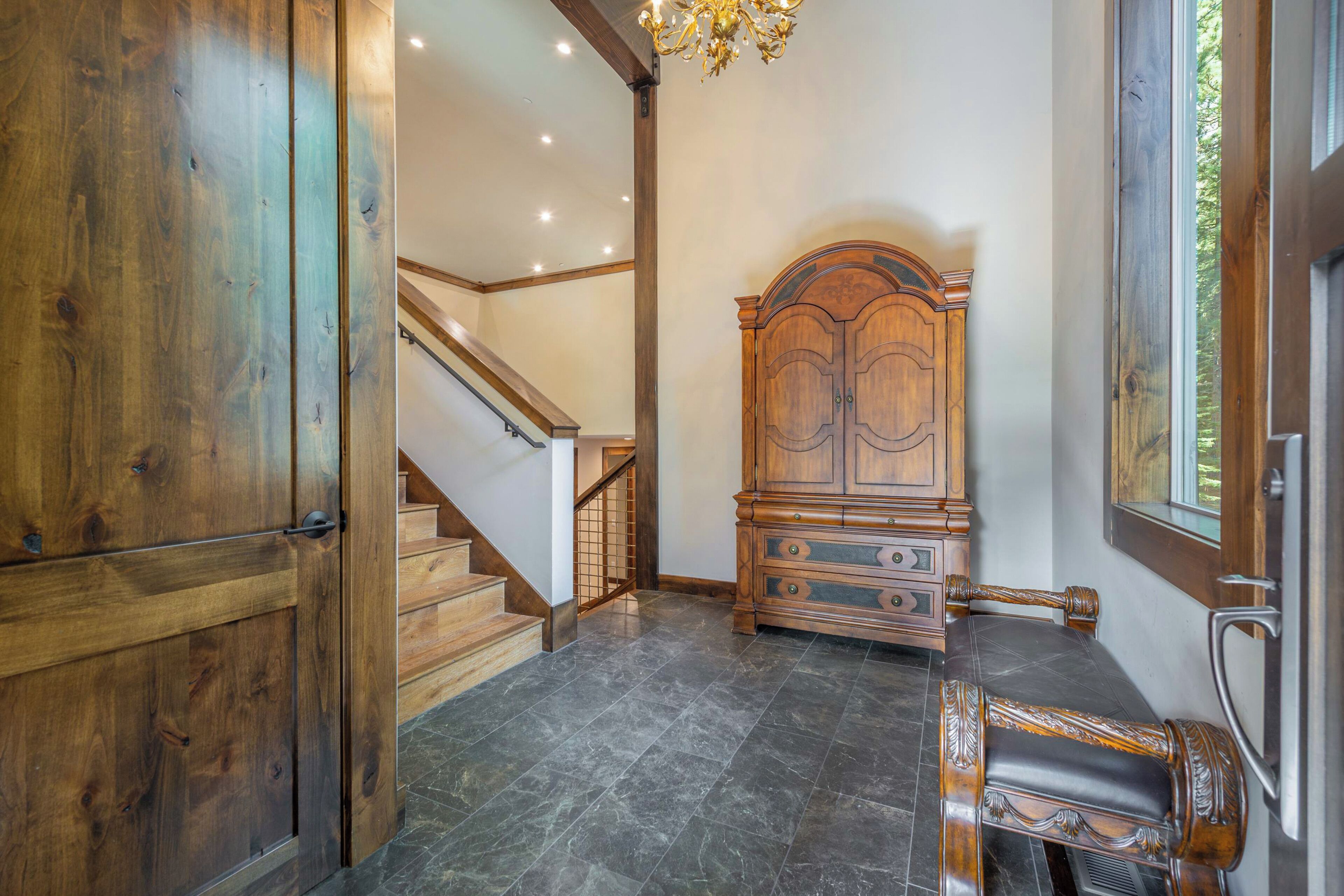 Une pièce avec une armoire en bois, un lit doté d’une tête de lit, un escalier et un lustre.