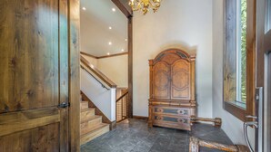 Ein Zimmer mit einem Holzschrank, einem Bett mit Kopfteil, einer Treppe und einer Chandelier.