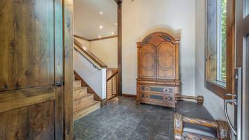 Une pièce avec une armoire en bois, un lit doté d’une tête de lit, un escalier et un lustre.