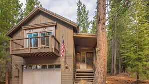 Eine zweistöckige Holzhütte mit Balkon, einer amerikanischen Flagge und einer Garage.