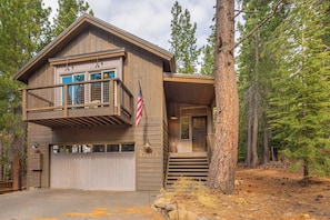A two-story wooden cabin with a balcony, a garage, and a flag. - 4BR Home w/ 2 Decks, Near Lake & Ski Resorts (Truckee)