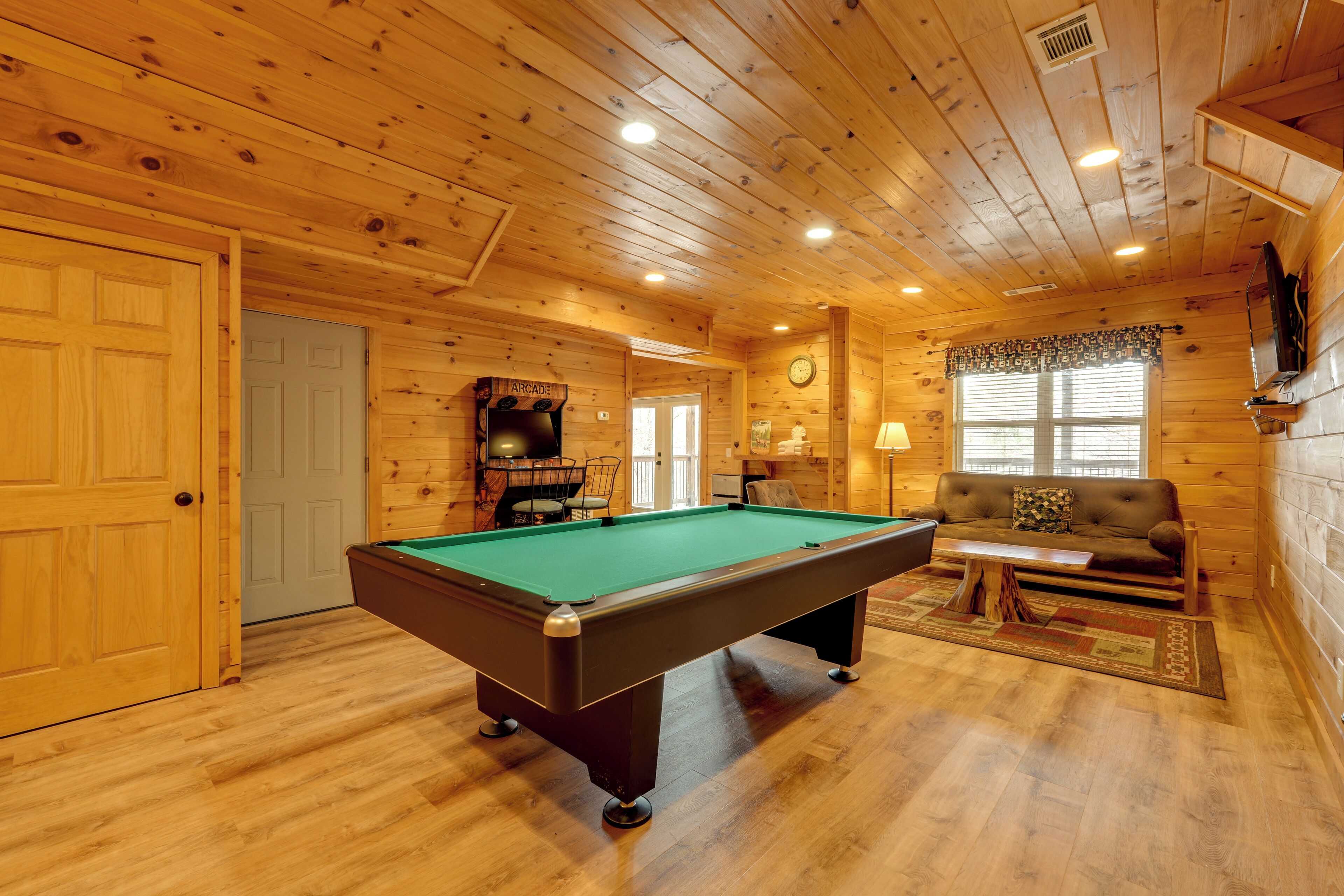 A wooden interior with a pool table, a sofa, and a television.