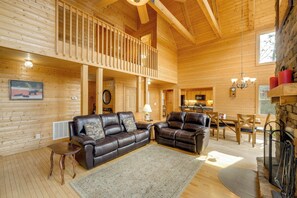 A wooden cabin interior with a balcony, leather sofas, a dining area, and a fireplace. - Blue Ridge Retreat: Epic Game Room & Luxe Hot Tub (Blue Ridge)
