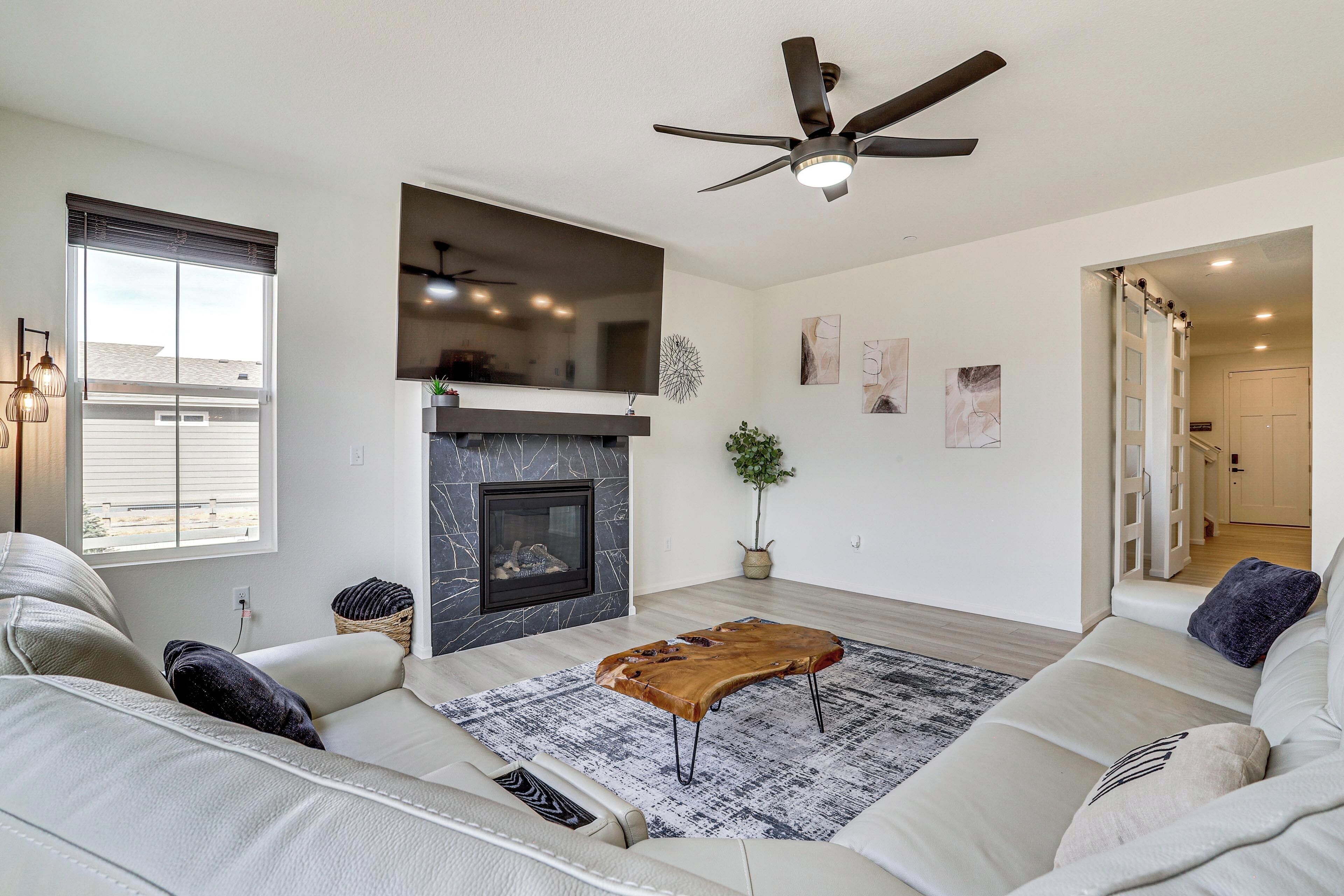 Olohuone, jossa on takka, sohva, kattotuuletin ja näkymä ulos.