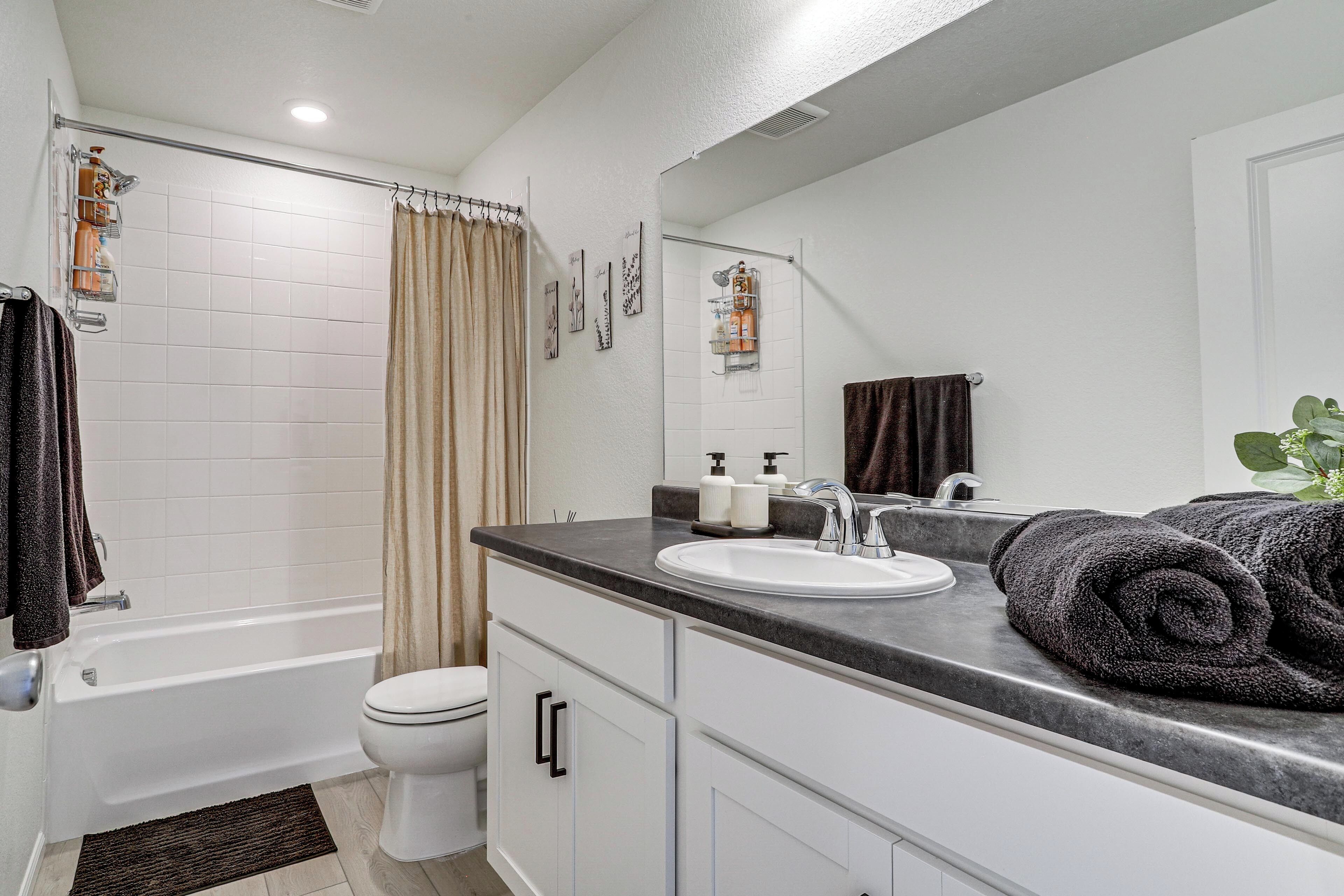 A bathroom with a bathtub, toilet, sink, and a mirror.