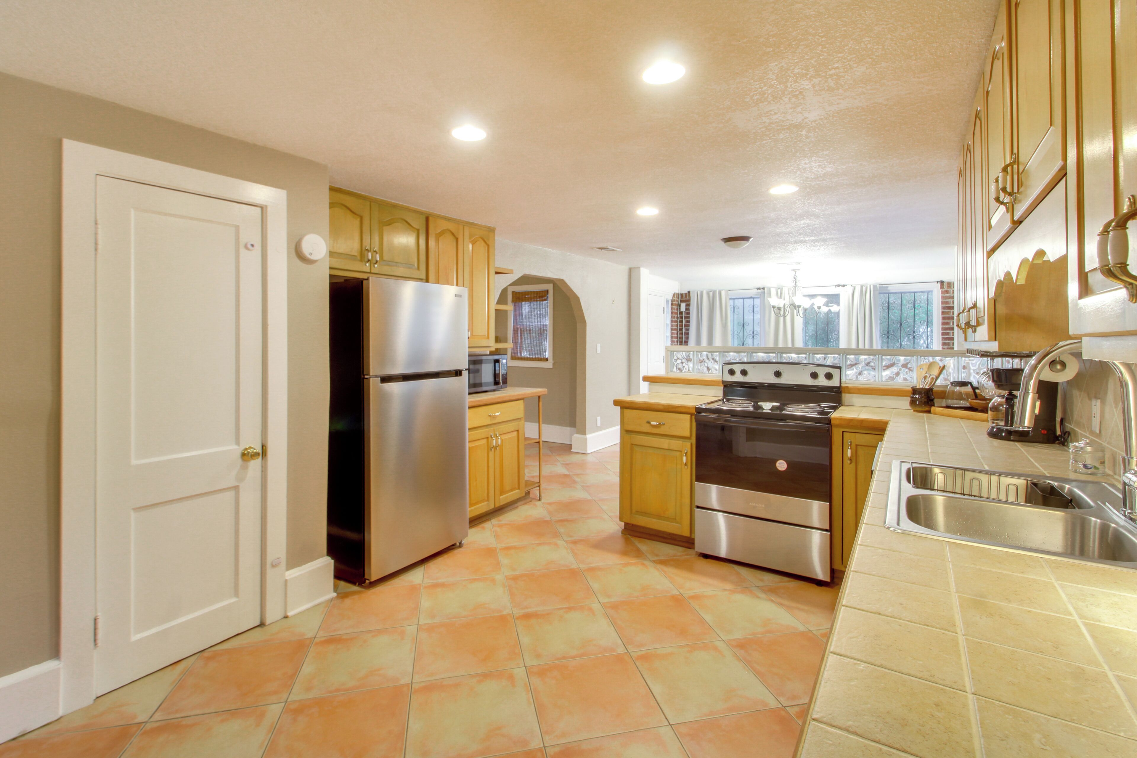 A kitchen with wooden cabinets, a stainless steel refrigerator, a stove, and a sink.