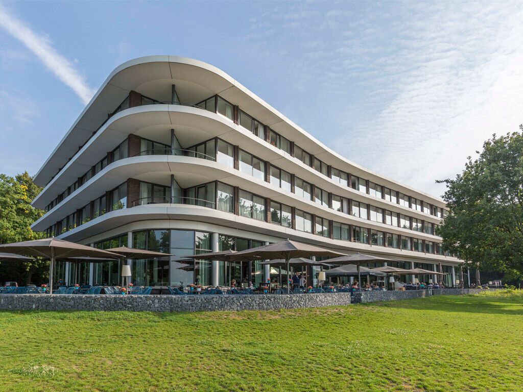 Arrive to sleek modern architecture framed by peaceful greenery.