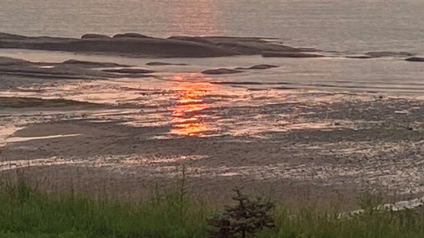 Un atardecer sobre un paisaje costero con horizonte plano y sin edificios ni estructuras visibles.