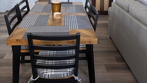 Un comedor con una mesa de madera, sillas negras y un sofá al fondo.