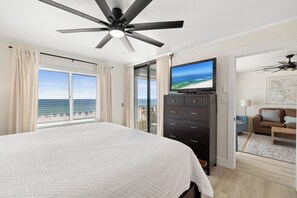 Habitación de hotel con cama, televisión, cómoda y vista a la playa.
