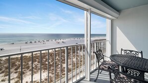A balcony with a view of the beach, a table with chairs, and a railing. - Summerchase 305 by Liquid Life (Orange Beach)