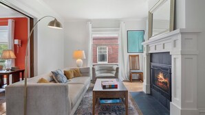 A living room with a sofa, armchair, coffee table, floor lamp, and fireplace. - Stylishly Renovated Retreat Just Steps from Dining & Entertainment (Petoskey)