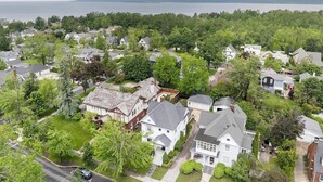 A residential area with houses, trees, and a body of water in the background. - Stylishly Renovated Retreat Just Steps from Dining & Entertainment (Petoskey)
