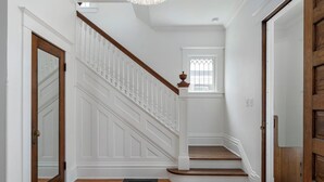 A staircase with white railings and wooden steps, leading to a landing with a small window. - Stylishly Renovated Retreat Just Steps from Dining & Entertainment (Petoskey)
