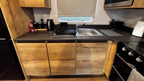 Une cuisine compacte avec des meubles en bois, un four à micro-ondes encastré et une cuisinière à gaz.